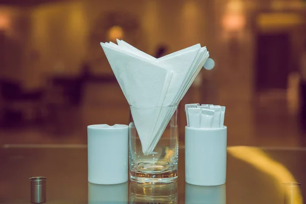 Λευκό χαρτοπετσέτες σε μεταλλική χαρτοπετσέτα, μπαχαρικά αλάτι και πιπέρι σε ένα ξύλινο τραπέζι, πανοραμική θέα. οδοντογλυφίδα. Τραπέζι σε καφετέρια ή εστιατόριο. — Φωτογραφία Αρχείου