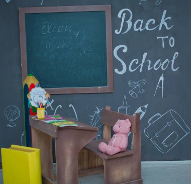 Masada mutlu gülümseyen öğrenci çizimleri. Arka planda karatahta olan sınıf odası. Çalar saat, kalemler, kitaplar. Sonbaharın ilk günü. Tahtaya yazı yazma kavramına dönelim. Okula geri dön..