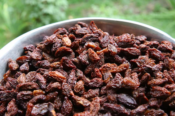 Sweet dry raisins close-up shot for green background . Many Raisins for background grape raisin texture .black raisins in the tray . — Stock Photo, Image