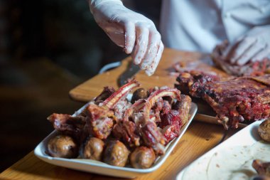 Barbekü kuzu etinden ya da koyun etinden yapılır ve slasher tarafından işlenir. Antrikot ve patates kebabı beyaz bir tabakta. Açık ateşte kızartılmış et, özel bir şekilde pişirilmiş..