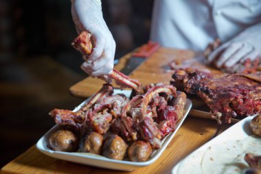 Barbekü kuzu etinden ya da koyun etinden yapılır ve slasher tarafından işlenir. Antrikot ve patates kebabı beyaz bir tabakta. Açık ateşte kızartılmış et, özel bir şekilde pişirilmiş..