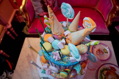 Pasta ve pasta için süsleme. Renkli kek, waffle külahında dondurma için, beyaz ahşap masa üzerine şekerleme serpiştirilmiş. Renkli küçük tatlı toplu mavi pasta .