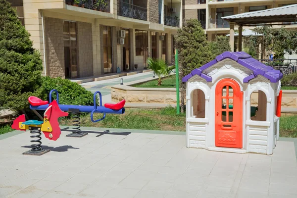 Área de entretenimiento.Casa de juegos para niños en el centro de entretenimiento. Casa de juegos para niños de plástico. Caballo de primavera en el patio. Balancín en parque infantil en parque. Caballo infantil. casa de plástico colorido  . —  Fotos de Stock