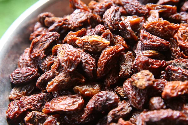 Black raisins in the wooden bowl. Sweet dry raisins close-up shot for background . Many Raisins for background grape raisin texture . — Stock Photo, Image