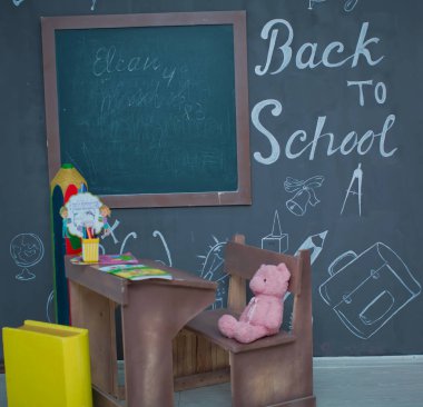 Masada mutlu gülümseyen öğrenci çizimleri. Arka planda karatahta olan sınıf odası. Çalar saat, kalemler, kitaplar. Sonbaharın ilk günü. Tahtaya yazı yazma kavramına dönelim. Okula geri dön..