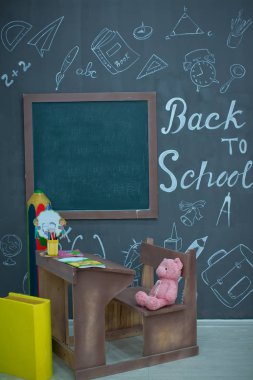 Masada mutlu gülümseyen öğrenci çizimleri. Arka planda karatahta olan sınıf odası. Çalar saat, kalemler, kitaplar. Sonbaharın ilk günü. Tahtaya yazı yazma kavramına dönelim. Okula geri dön..