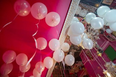 Düğün ya da çocukların doğum günü partisi dekorasyonu. Helyum balonları kırmızı yüzer. Beyaz balonlar parti için odadaki beyaz tavanda yüzüyor..