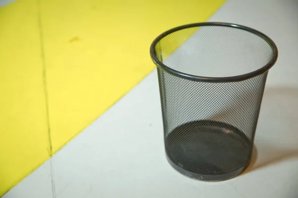 Male hand throwing crumpled paper into metal trashcan . School and office equipment. black iron trash bin white and yellow . Image of man's hand throwing paper in the dustbin . — Stock Photo, Image