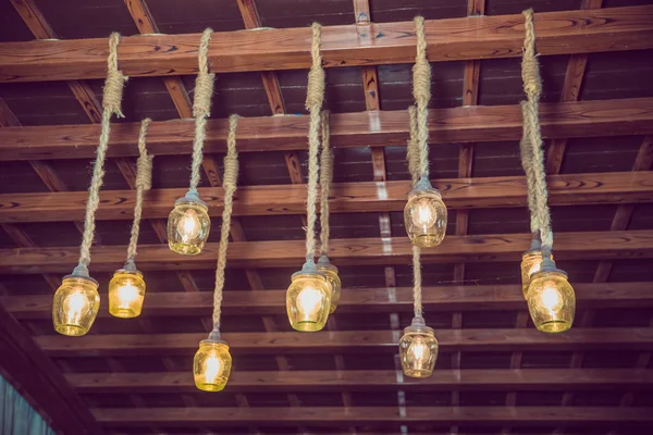 Clásicos diferentes bombillas retro colgando en el fondo de la pared de ladrillo por la noche. techo de madera. cable. Hermosa decoración de lámpara de luz retro de lujo brillante . —  Fotos de Stock