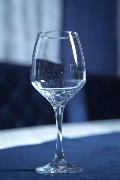 Επιτραπέζια σκεύη στο τραπέζι στο καφενείο, εστιάστε στο κοτσάνι από γυαλί κρασιού. Κομψή ρύθμιση τραπεζιού. Μπλε φόντο Μπακάλ. Κενό ποτήρι κρασιού. — Φωτογραφία Αρχείου