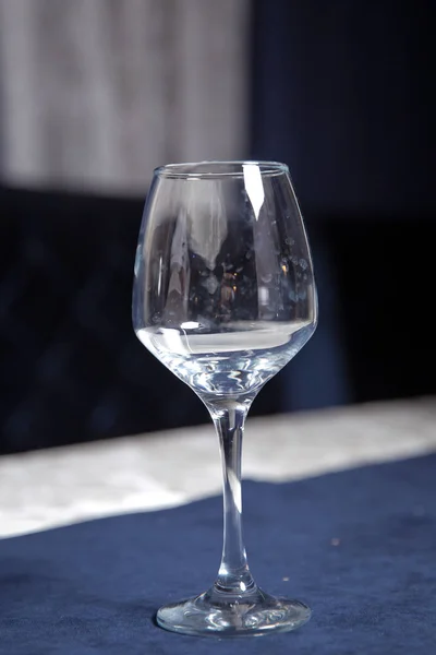 Επιτραπέζια σκεύη στο τραπέζι στο καφενείο, εστιάστε στο κοτσάνι από γυαλί κρασιού. Κομψή ρύθμιση τραπεζιού. Μπλε φόντο Μπακάλ. Κενό ποτήρι κρασιού. — Φωτογραφία Αρχείου