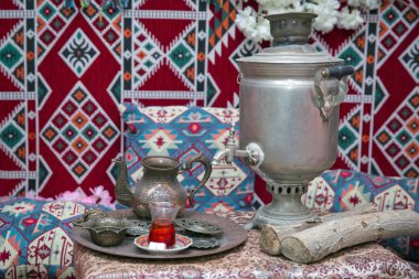 Samovar on a background of carpet . Tea in the tablecloth cups . Copper teapot . Copper bowl . Samovar and teapot .