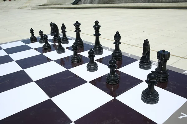 Textura, fondo. Antecedentes Gran ajedrez en el parque. Gran juego de ajedrez en el suelo en el parque. Grandes piezas de ajedrez jugando al juego en el piso. Ajedrez gigante en el tablero ubicado en el suelo  . — Foto de Stock