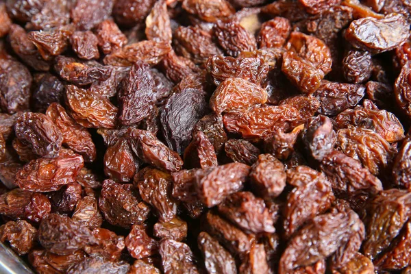 Black raisins in the wooden bowl. Sweet dry raisins close-up shot for background . Many Raisins for background grape raisin texture . — Stock Photo, Image