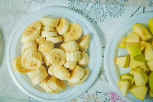 Cortar el plátano en un recipiente de plástico. Rebanadas de plátano en tazón sobre fondo de piedra con espacio para copiar. Snack saludable de vitaminas naturales. Vista superior, plana. El plátano picado está en un recipiente de plástico  . — Foto de Stock