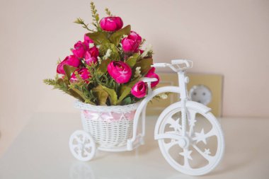 Beautiful flowers decorated in wedding . Bicycle toy carry pink flowers on the table .