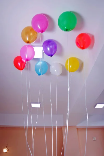 Balões coloridos e vermelhos flutuam no teto branco na sala para a festa. Casamento ou crianças decoração de festa de aniversário interior. Balões de hélio  . — Fotografia de Stock