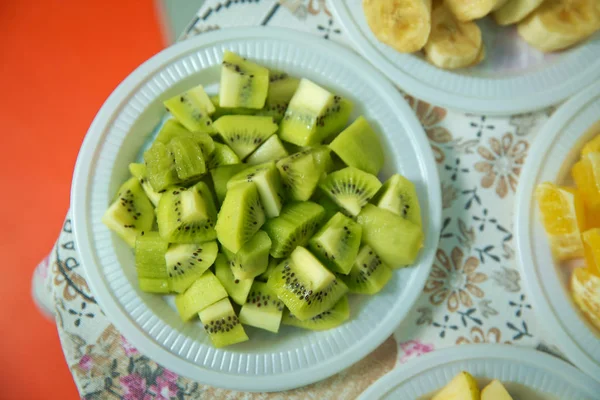 Cut kiwi in a plastic bowl. Banana slices in bowl over stone background with copy space. Healthy natural vitamin snack. Top view, flat . The chopped kiwi is in a plastic bowl .