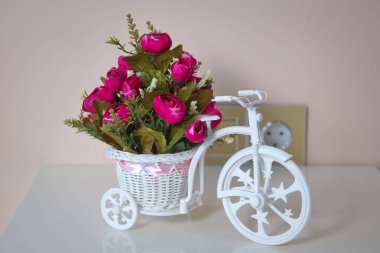 Beautiful flowers decorated in wedding . Bicycle toy carry pink flowers on the table .