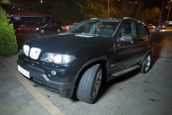 Der Autoscheinwerfer auf neblig. Abend für Abend. Abend Nacht. Nachts brennt das Auto lichterloh. schwarzer dunkler Luxus in der Nacht mit wütenden Scheinwerfern für Tapete und Hintergrund — Stockfoto