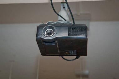 İçerideki tavan üzerinde beyaz bir projektör. Tavanda modern video projektörü var. Siyah Projektör büyük toplantı odasında ya da üniversitede beyaz tavanda asılı.