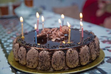Super chocolate cake with chocolate sauce . Piece of chocolate cake with icing . The cake candles are lit . Delicious vegan chocolate cake. Selective focus.