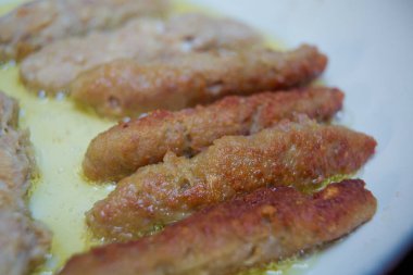 Uzun pirzola kırmızı bir tavada kızartıldı. Pirzolayı beyaz bir tavada pişiriyor. Sulu ev yapımı pirzola biftek, domuz eti, tavuk. .