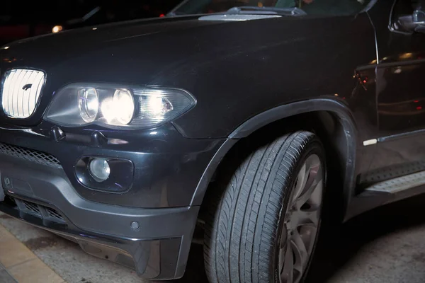 Der Autoscheinwerfer auf neblig. Abend für Abend. Abend Nacht. Nachts brennt das Auto lichterloh. schwarzer dunkler Luxus in der Nacht mit wütenden Scheinwerfern für Tapete und Hintergrund — Stockfoto