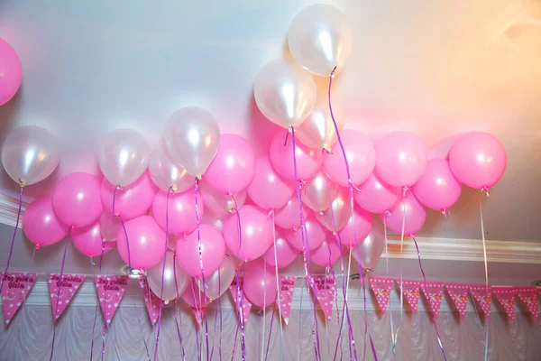 Wedding or children birthday party decoration interior . Helium balloons . Pink and white balloons float on the white ceiling in the room for the party.