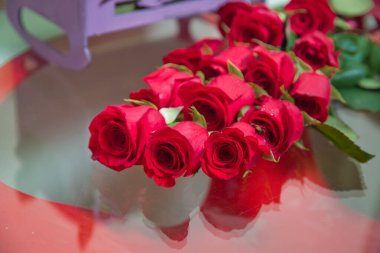 Gelin buketi. Camda, aynada bir düğün buketinin yansıması. Çiçekler masanın üzerinde yatıyor. Cam bir masanın üzerinde gül kolyesi aranjmanı.