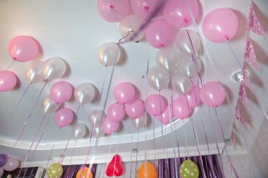 Wedding or children birthday party decoration interior . Helium balloons . Pink and white balloons float on the white ceiling in the room for the party.
