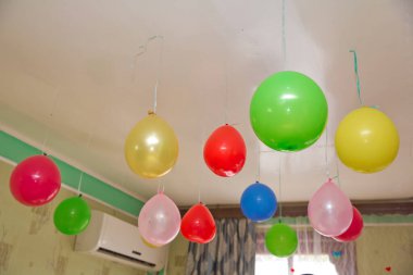 Colorfull and red balloons float on the white ceiling in the room for the party. Wedding or children birthday party decoration interior . Helium balloons .