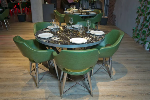 Bovenaanzicht kopieerruimte. Ronde marmeren tafel. Groene stoel. Set van bestek mes, lepel, vork, bord, wijnglas. Zwarte marmeren tafel . — Stockfoto