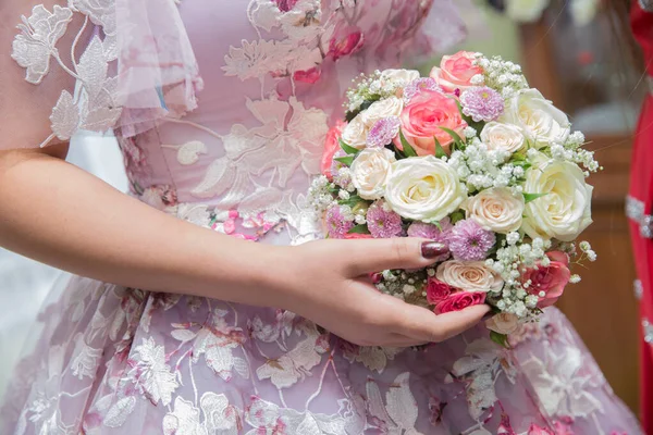Νύφη και γαμπρός χέρια με λευκά λουλούδια γάμου και ροζ νυφικό φόρεμα. Χέρια νύφης και γαμπρού με λουλούδια γάμου. Γάμος ζευγάρι κρατά τα χέρια . — Φωτογραφία Αρχείου