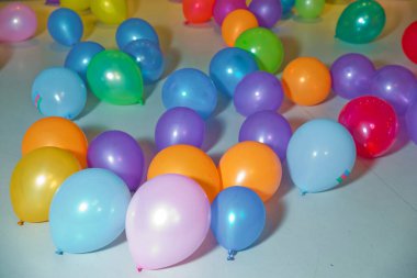 Yerde farklı renkte balonlar var. Renkli balon yatağı. Tatil, çocuk partisi, oyun odası, küçük renkli toplarla dolu bir kutu.
