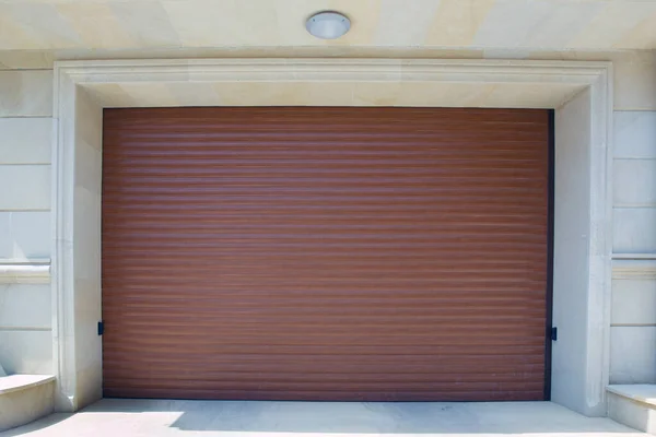 Otomatik elektrikli çekiş kapısı ya da modern binanın zemin katındaki şınav kapısı. Kepenk ya da paten kapısı ve beton zemin dışarıda. Bir evdeki kahverengi otomatik panjurlar. Garajdaki kapılar