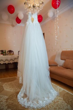 Beyaz gelinlik odadaki bir avizeye asılı. Gelinin odasındaki mükemmel gelinlik. Düğün fotoğrafçılığı. Güzel beyaz gelinlik. Gelin sabahı