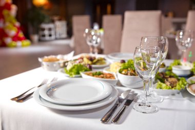 Tatil masası, çatal bıçak takımı, çanak çömlek, bardak, tabak, çatal. Salata ve diş eti. Beyaz masada kaşıklı, çatallı ve bıçaklı bir tabak. Masa beyaz masada. .