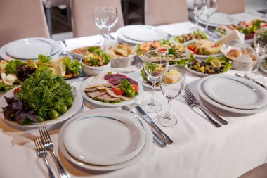 Tatil masası, çatal bıçak takımı, çanak çömlek, bardak, tabak, çatal. Salata ve diş eti. Beyaz masada kaşıklı, çatallı ve bıçaklı bir tabak. Masa beyaz masada. .