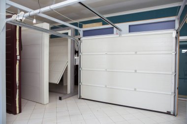 Otomatik elektrikli çekiş kapısı ya da modern binanın zemin katındaki şınav kapısı. Kapalı kapı ya da patenli kapı ve beton zemin. Beyaz otomatik panjurlar. Garajdaki kapılar