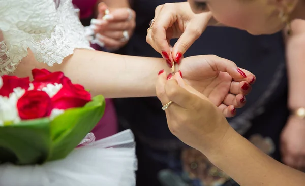 Bridesmaid helps to put a bracelet on his arm for the bride. bride putting on jewelry, focus on bracelet. Close up of groom giving his bride bracelet as symbol of his love on their wedding day.