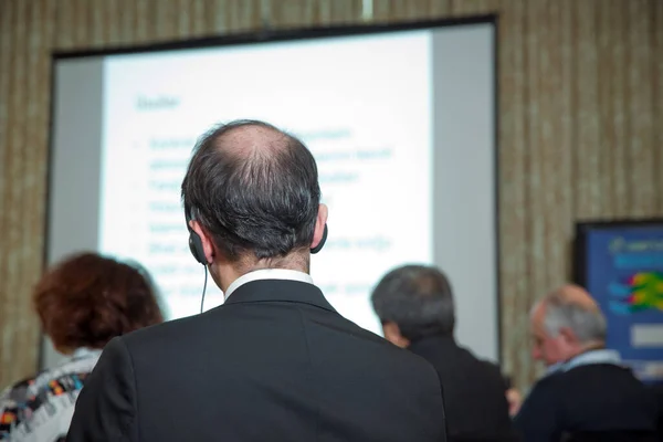 会议上戴着耳机的人 观众穿着头电话进行在线翻译 在活动期间使用耳耳耳机进行翻译的无法辨认的人 — 图库照片