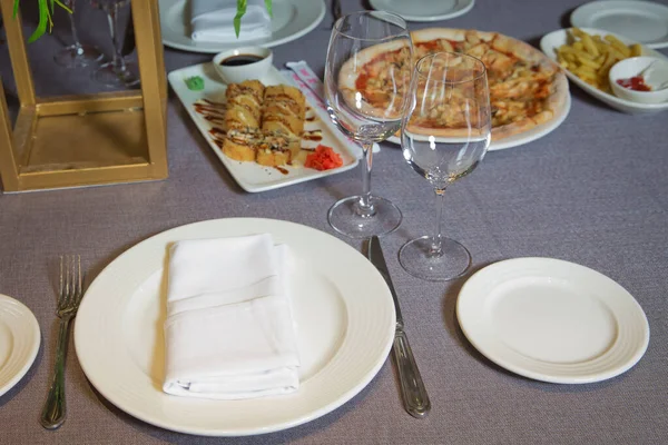 Tische zum Essen gedeckt. Gabel, Messer, Tischtuch vorhanden. Pizza, Pommes frites. Leere Gläser und Teller auf dem Tisch im Restaurant . — Stockfoto