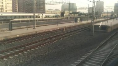 Yolcu treninin penceresinden yaklaşan bir yolcu gemisi. Tren yolu penceresi. Otoyol manzarası. Hareket halindeki trenin penceresinden bak. Manzarada demiryolu var. Dışarıya bak. 