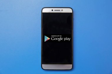 Android Google Oyun Mağazası logosu olan akıllı telefonu ekranda tutan adam.