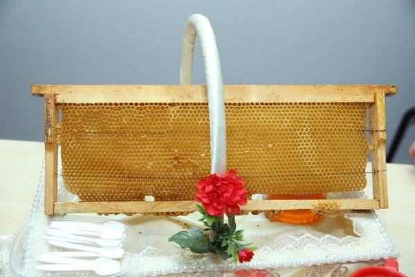 Honeycombs frame with fresh honey . wooden honey dipper and honeycombs in wooden frame with full cells of honey sealed with wax, tools for beekeeping on wooden table. Beekeeping concept.