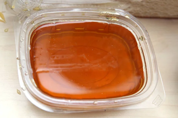 Φυσικό μέλι προς πώληση σε πλαστικά δοχεία. μέλι σε πλαστικό κουτί σε λευκό φόντο . — Φωτογραφία Αρχείου