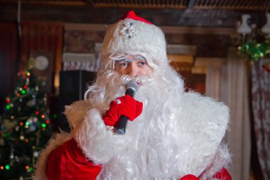 Bakü, Azerbaycan. 12.01.2018. Noel Baba aleyhinde Noel şarkıları söylüyor. Noel Baba kostümlü bir adam mikrofonla poz veriyor. Peder Frost mikrofonla konuşuyor. .