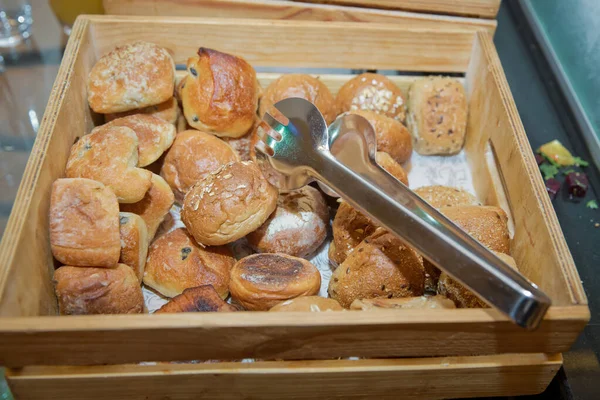 ペイストリーとガーリックブレッドは 木製の箱とスチール製のグリッパー スパチュラで提供されます 木のバスケットにパン 朝食ビュッフェでは 木製の箱にパンの様々な種類 ホテルオープンビュッフェパン — ストック写真