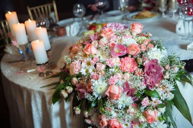 Çiçekler düğün masasının üstünde. Düğün masası dekorasyonu. Restoranda renkli düğün seti dekorasyonu. Masada çiçekler var. Çiçek masa dekorasyonu şeffaf vazolarda mumlarla
